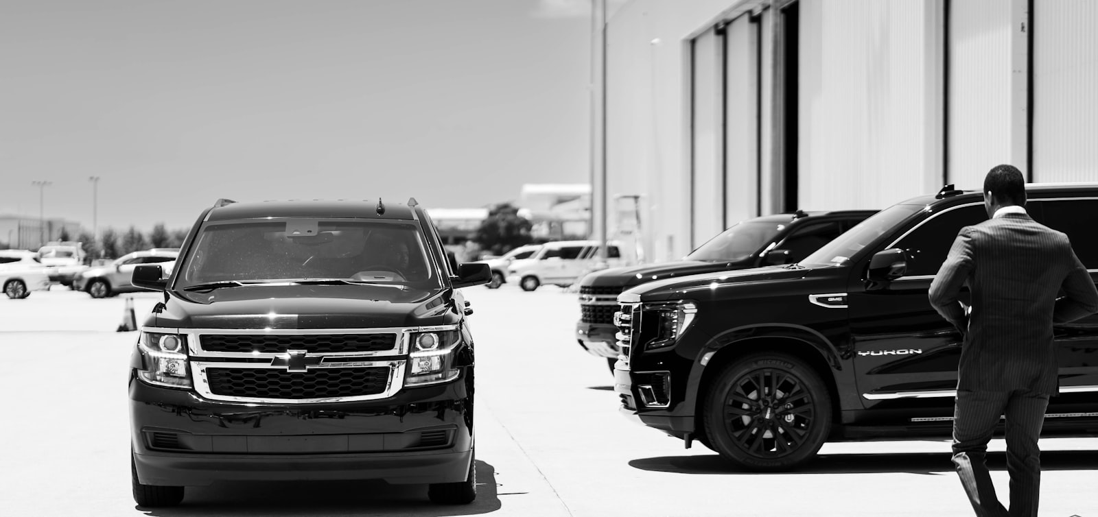 A chauffeur walking a staged line of black livery SUVs