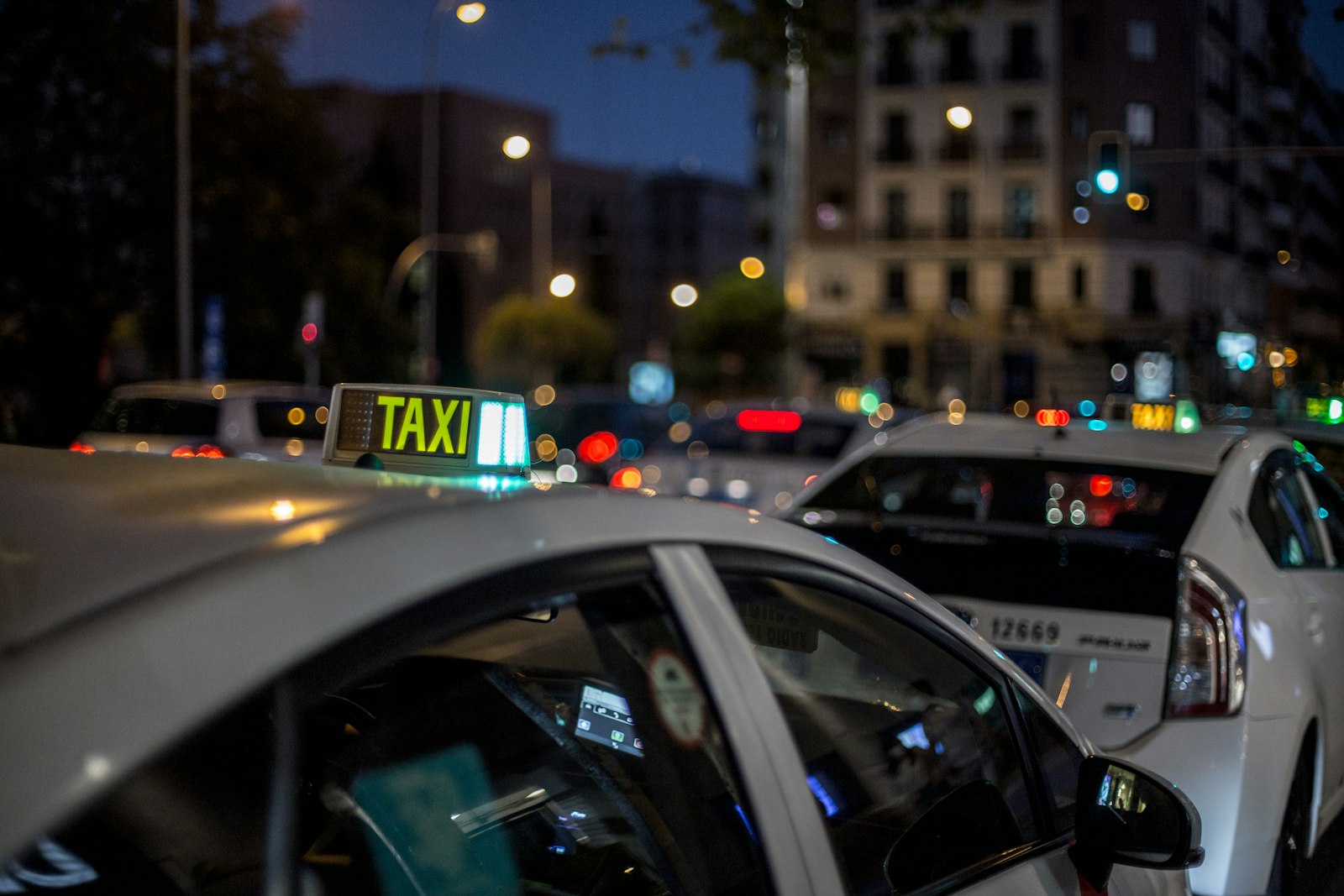 A taxi with its rooftop light on, waiting in a city street at night